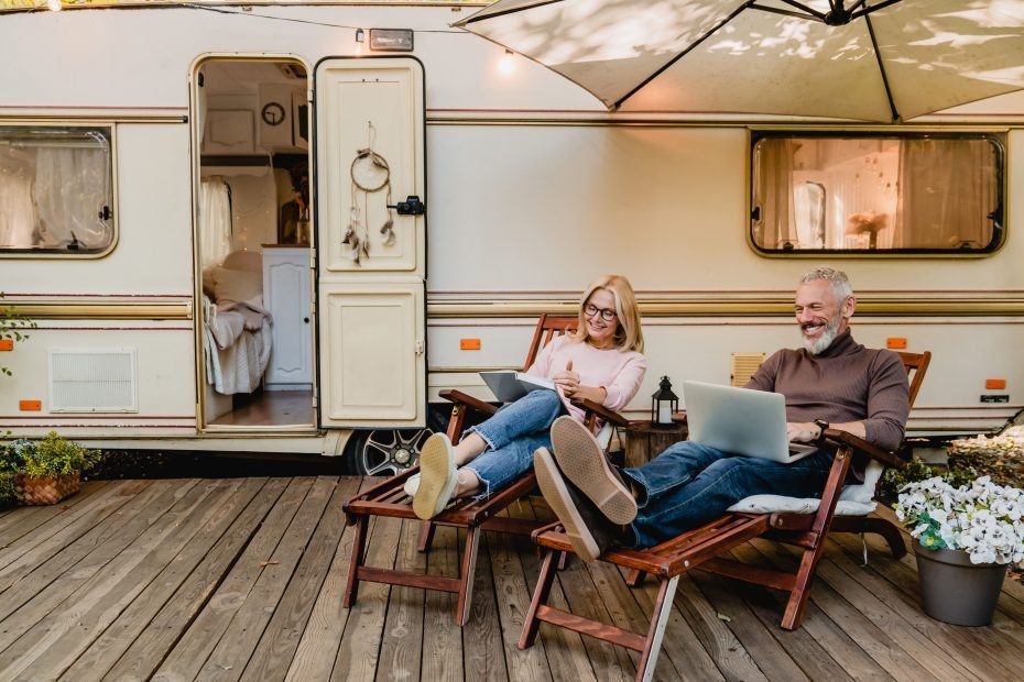 couple relaxing on deck chairs by RV