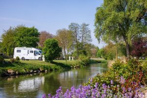 Small camper van parked near river campsite solo camping location